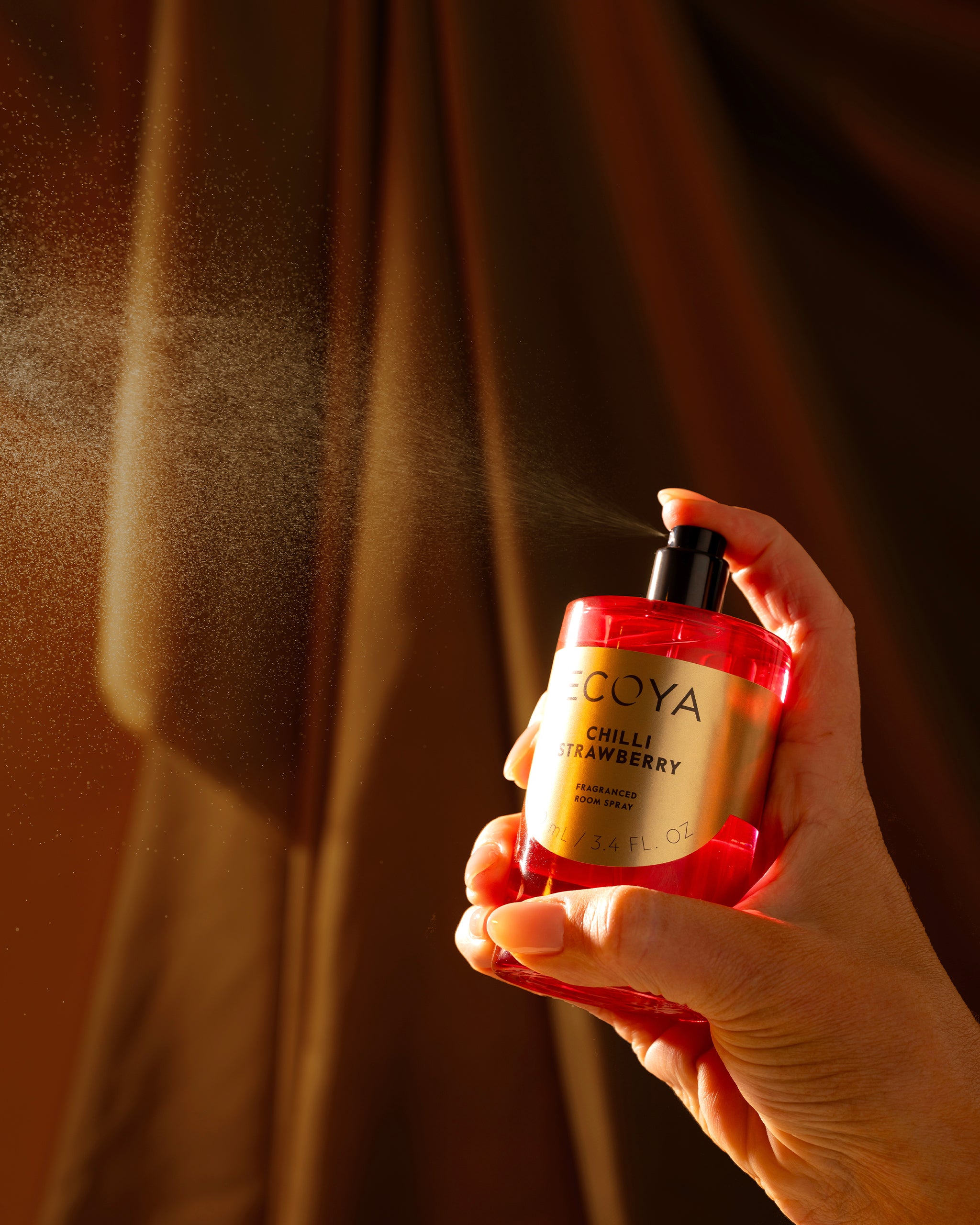 hand spraying ecoya room spray from the holiday collection featuring limited edition fragrances